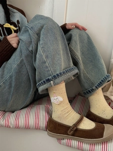 Close-up of beige crew socks featuring cute cartoon embroidery and dotted yarn pattern