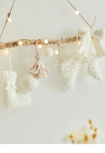 Close-up of cream knit Christmas ornaments with LED lights on rustic branches