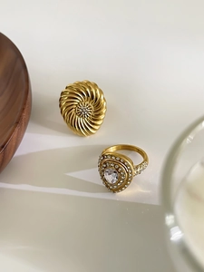 Close-up of golden spiral ring and heart-shaped band with sparkling rhinestones
