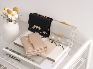 Detailed view of floral print wallets with gold leaf accents and metal clasp closure