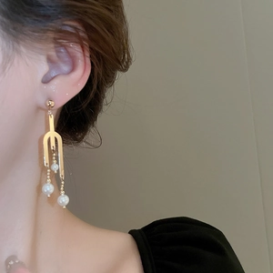 Long gold fork earrings with hanging pearls shown on a model for elegant dangle effect
