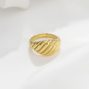 Macro shot of gold croissant ring with twisted texture on soft white fabric background