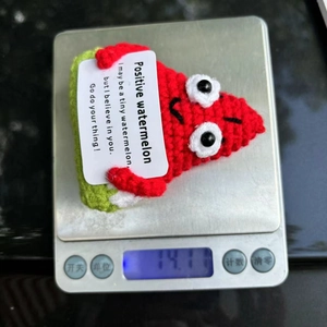 Detailed close-up showing a 14.1g handmade crochet watermelon on a digital scale
