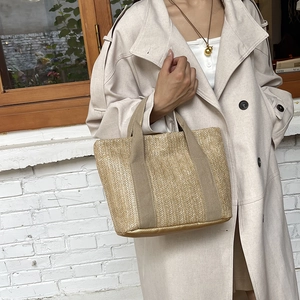 Detail of straw woven handbag with fabric handles shown in a natural outdoor cafe setting