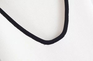 Détail de l'encolure contrastée avec texture en maille et coutures de précision