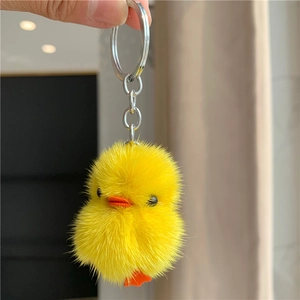 Detail of yellow plush duck keychain with silver metal ring and soft mink fur texture