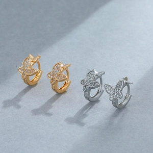 Macro detail of gold and silver butterfly hoop earrings featuring micro-paved zircons