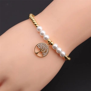 Detail of gold beads and white pearl bracelet with sparkling tree of life charm