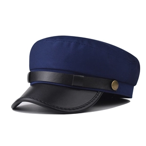 Detail of navy baker boy hat featuring black PU leather brim and vintage bronze button