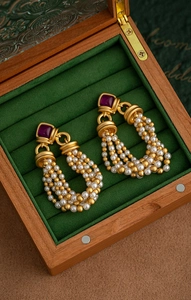 Detail of vintage palace style earrings with purple gemstones and pearls in a jewelry box