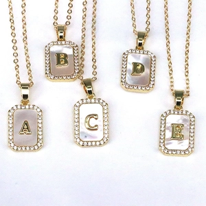Close-up of 18K gold rectangular necklaces with shell inlay and zircon letter charms