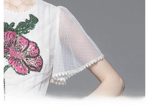 Détail de la broderie florale rose et des perles sur les manches en tulle transparent