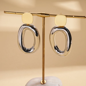 Macro shot of 18k gold and silver plated geometric oval earrings on a gold stand