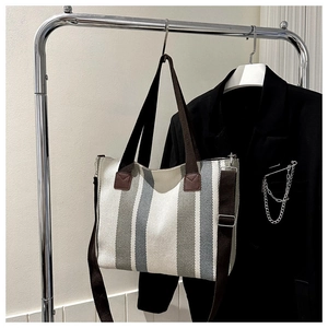 Detailed texture of a striped canvas tote bag with brown leather accents on a hanger