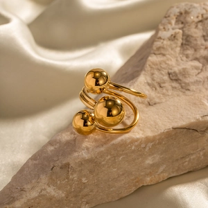 Detailed view of gold triple sphere stainless steel ring on natural stone background