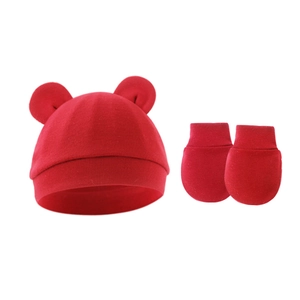 Detail shot of newborn red cotton knit hat with round ears and matching anti-scratch mittens
