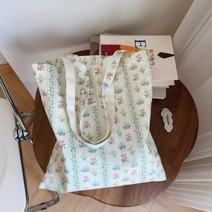 Dettaglio della stampa floreale e a righe su borsa tote in tela bianca su tavolo scuro