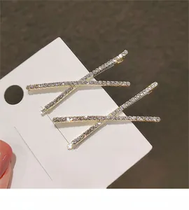 Makroaufnahme von zwei goldenen X-Haarspangen mit funkelnden Strasssteinen auf Karte