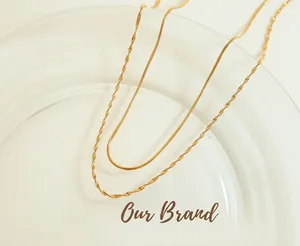 Macro view of gold double-layered flat snake and twisted link necklace on a porcelain plate