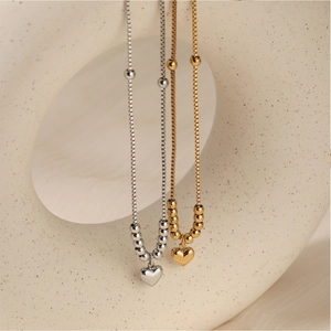 Elegante Halsketten aus Edelstahl mit Herzanhänger in Gold und Silber auf Keramikdekor
