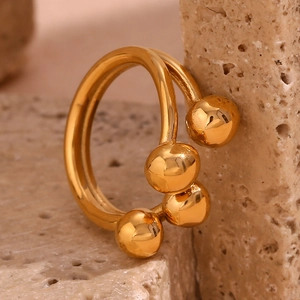 Macro detail of 18K gold plated beaded ring on a textured stone surface