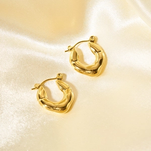 Vintage irregular golden hoop earrings on champagne silk background with soft lighting