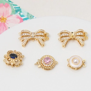 Detailed view of gold pavé zircon clasps in floral and bow shapes for DIY pearl jewelry