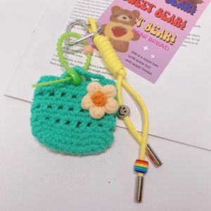 Détail d'un mini porte-clés pochette tressé vert avec des breloques fleurs et perles
