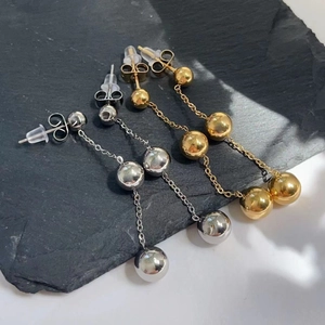 Detailed view of long ball tassel drop earrings in gold and silver finish with double backings