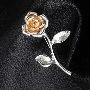 Detailed macro view of a two-tone rose brooch with gold center and silver petals