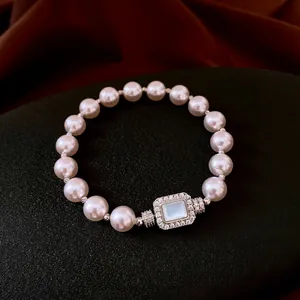 Elegant French style pearl bracelet featuring a crystal-encrusted square clasp and blue stone
