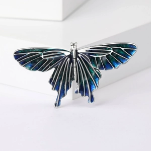 Detail of a butterfly brooch with silver metal frame and blue-green gradient enamel
