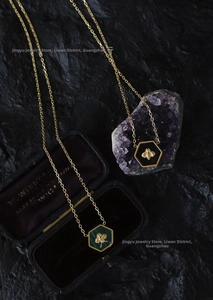 Detail of bee honeycomb necklaces in black and green malachite textures with gold chains
