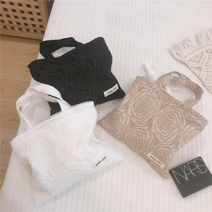 Detail of elegant 3D embossed rose pattern on textured fabric handbag with woven label