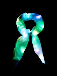 Detail showing glowing LED satin scrunchie with long ribbons in dark lighting