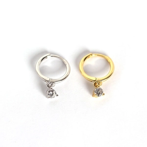 Detail of silver and gold huggie earrings with round-cut cubic zirconia dangle charm