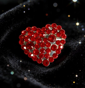 Macro shot of silver heart brooch with shimmering red rhinestones on black velvet