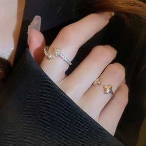 Close-up of sparkling star-shaped silver open rings on fingers with a black suit backdrop