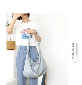 Detail of light blue nylon shoulder bag featuring creative pleated strap design