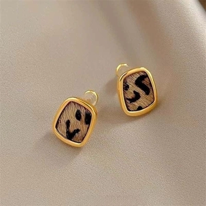Detailed close-up of gold-plated square hoop earrings with leopard print plush texture