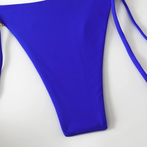 Detail of cobalt blue bikini bottom featuring side tie strings and gold metal O-ring
