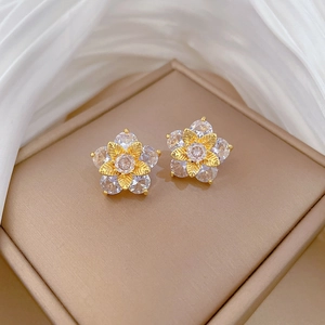 Macro detail of gold-plated five-petal flower stud earrings with sparkling cubic zirconia