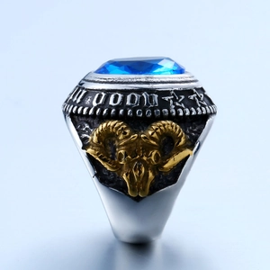 Close-up of vintage steel ring featuring blue gemstone and golden ram head relief detail