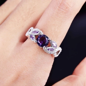 Macro shot of silver ring with purple amethyst stone and floral vine texture on finger