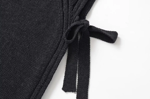 Gros plan d'un gilet en tricot noir avec lacets latéraux et texture de tissage