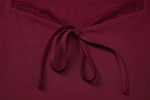 Dettaglio macro della canotta bordeaux con bordo in pizzo e chiusura a fiocco