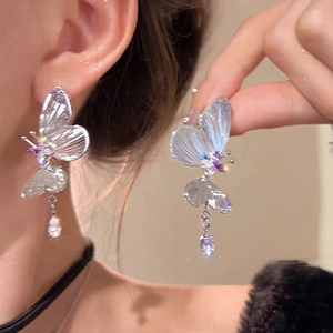 Gros plan de boucles d'oreilles papillon à pompons avec zircons portées par un mannequin
