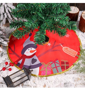 Detail of red Christmas tree skirt with snowman and gift box prints on snowy background