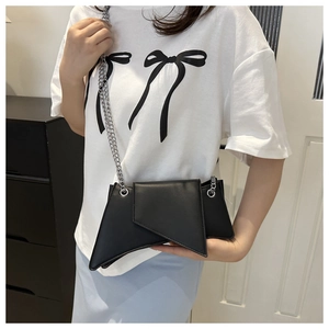 Detail of a black geometric crossbody bag featuring an edgy asymmetrical design with chain strap