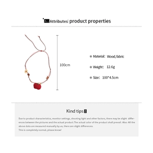 Detail showing fabric beaded necklace with red wooden apple pendant and product dimensions